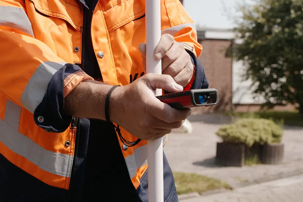 Mitarbeiter misst mit einem Lasermessgerät an der Baustelle