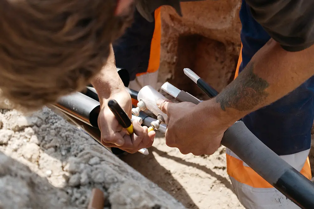 Monteure setzen eine Verbindungsmuffe an einem Stromkabel