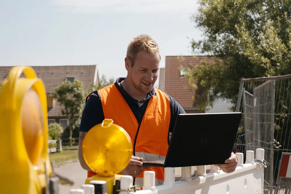 Site manager with a laptop at a construction site barrier